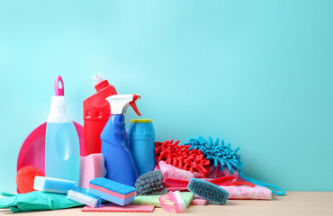 Set of cleaning supplies on table against color background