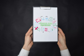 In the hands of a businessman a notebook with the inscription:PERSONAL DATA PROTECTION