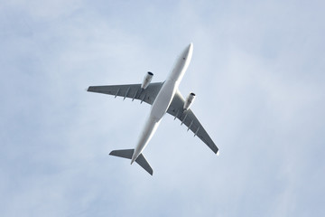 Fototapeta na wymiar Travel, transportation, aviation concept, copy space/ Wide-body passenger airplane flying overhead against a spring blue sky, bottom view