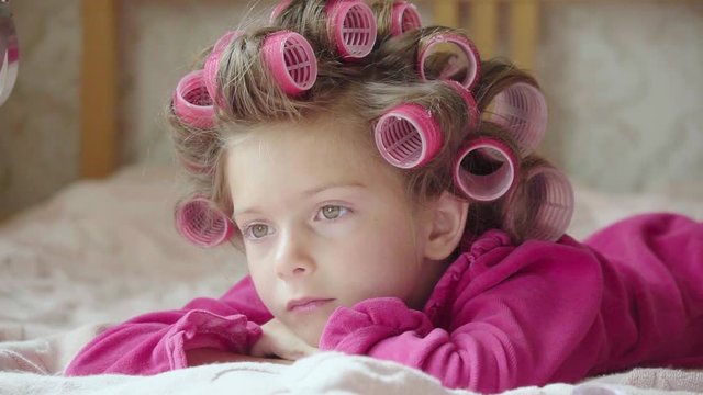 Funny little girl with curlers and lilac dress