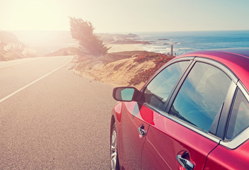 Fototapeta na wymiar Red car close-up on the road near the ocean