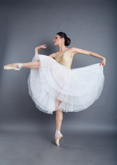 Naklejka premium Beautiful slim woman ballet dancer in studio isolated on gray