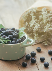 Fresh ripe wild blueberries heap in bowl on wood table under sunlight in vertical for background or wallpaper. Healthy and delicious fruits concept. Blueberry is a high antioxidant food and vitamin C.