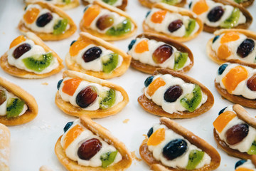 cakes with pieces of fruit cream are on a baking tray and ready to eat, background