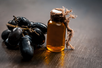 Close up of Black grapes oil on a wooden surface in dark  Gothic colors  to improve overall hair...