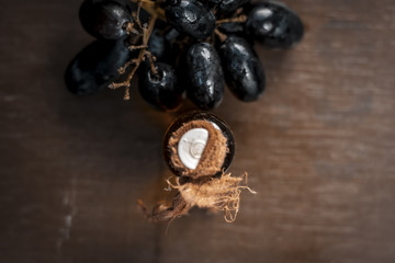 Close up of Black grapes oil on a wooden surface in dark  Gothic colors  to improve overall hair...