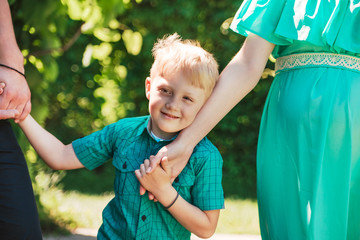 Little boy holding his mother's hand.Family cute moments.Parents and son.Outdoor.