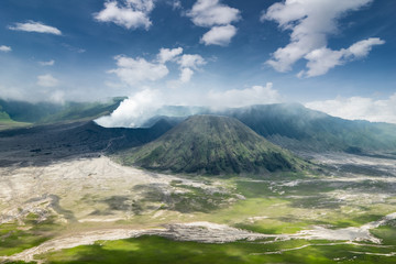 Fototapeta na wymiar Clouds of smoke coming from crater of Mount Bromo and drifting by, Tengger Semeru national park, East Java, Indonesia. Landscape with erupting volcano in sunny day. Eruption and volcanic activity.