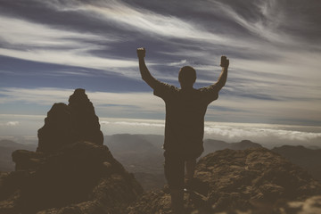 Silhouette man raising up hands on mountain on Gran Canaria island.