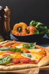 close up of appetizing tasty pizza with cherry tomatoes and basil