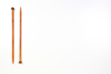 A pair of wooden knitting needles on white background.
