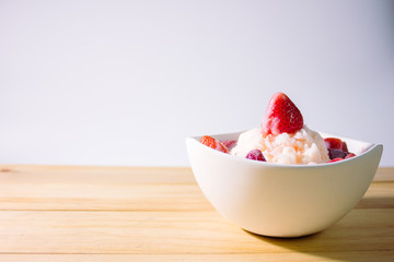 Homemade strawberries bingsoo on wooden table with white background side view.