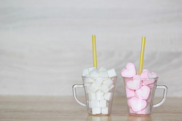 Unhealthy food concept, white sugar and sweet marshmallow in white cup on the wooden table