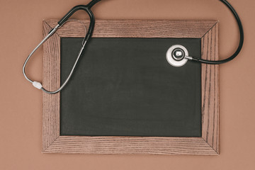 top view of blank chalkboard and stethoscope isolated on beige surface, world health day concept