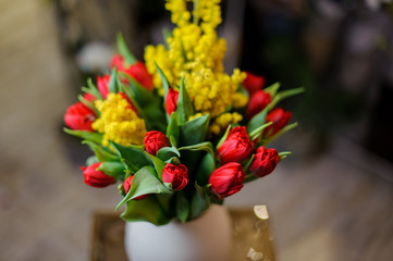 Beautiful red tulips and yellow mimosa in a vase
