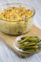 Baked meal from pasta, smoked meat and eggs called sunkofleky served with pickles