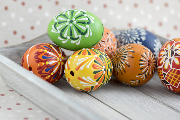 Group of wax painted Easter eggs on light grey tray