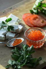  bright photo of tomatoes, red caviar, feta on a wooden board