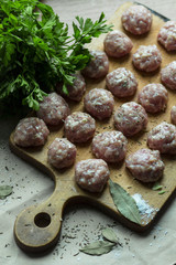  meat balls with greens and seasonings on a wooden board