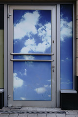 Mit Wolken beklebte Tür  / Eine mit einem blauen Himmel und Wolken beklebte Eingangstür.