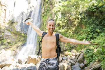 Fototapeta na wymiar Attractive man standing by waterfalls on his back