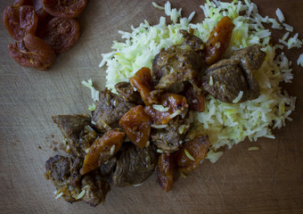  rice with meat, spices and dried apricots on a wooden tray