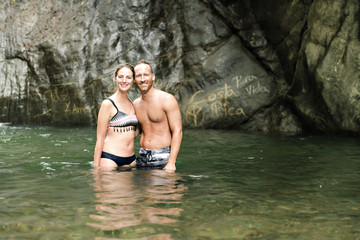 Attractive couple under jungle waterfall
