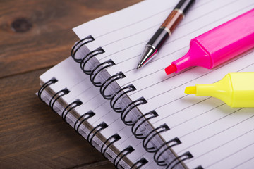 Spiral notebook rings next to ballpoint pen and pink and yellow marker. Mockup.