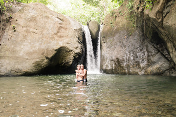 Attractive couple under jungle waterfall