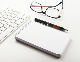 Background of workplace with keyboard, notebook, pen and glasses on white background. Business...