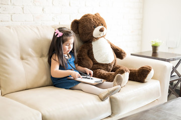 Cute little doctor girl playing with teddy bear
