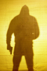 The shadow behind fabric of a man with a gun.