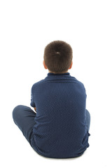 Back view of little boy sitting on floor looking at wall. Rear view. Isolated on white background 