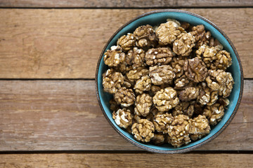 Close-up of a bowl with walnuts on a vintage wooden background. Top view, background.