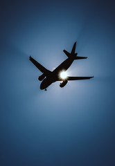 Silhouette von einem Flugzeug im Landeanflug vor der strahlenden Sonne