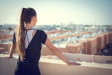 Back view of young woman with ponytail looking at city.