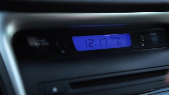 a video of a hand pushing the hour button on a car clock to change the time 
