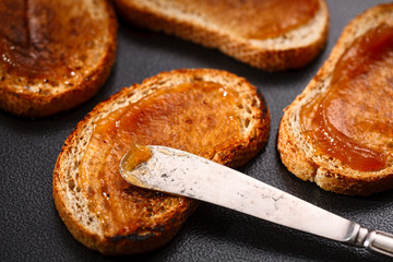 toasts with apple jam and knife on black background. Top view