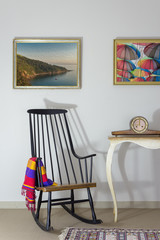 Vintage Furniture: Rocking chair and antique desktop clock on old style vintage table on background of off white wall with two hanged paintings including clipping path for paintings