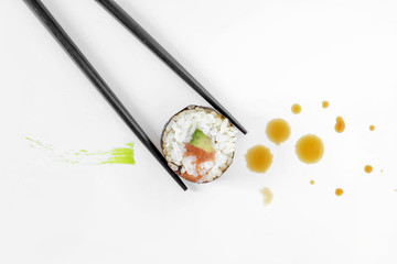 Sushi rolls and chopsticks with splashes of soy sauce and brush strokes of wasabi. Concept design.  Japanese cuisine.