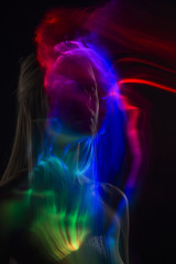 Conceptual avant-garde silhouette portrait of a beautiful blonde girl covered with multicolored lines applied by a lightbrush