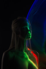 Conceptual avant-garde silhouette portrait of a beautiful blonde girl covered with multicolored lines applied by a lightbrush
