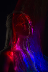Conceptual avant-garde silhouette portrait of a beautiful blonde girl covered with multicolored lines applied by a lightbrush