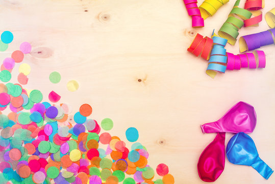 Colorful confetti and streamer on wooden background from above