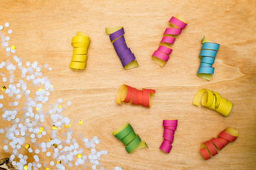 Fototapeta na wymiar Colorful confetti and streamer on wooden background from above