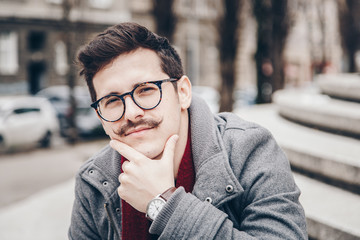 fashion portrait of a attractive hipster man outside. handsome guy with a vintage mustache,...