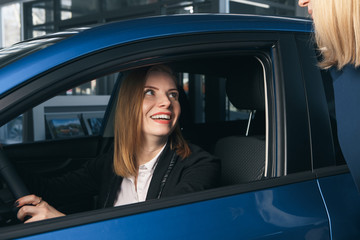 Young smiling woman getting keys of a new car. Concept for car rental