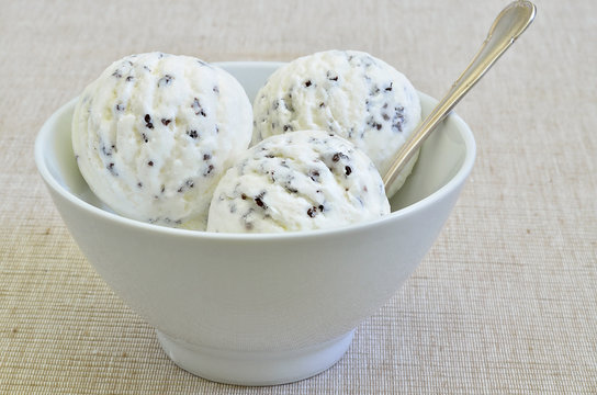 Stracciatella Eiscreme / Stracciatella Eis in einer wei&szlig;en Schale auf beigem Hintergrund, Nahaufnahme, Makro, Format f&uuml;llend
