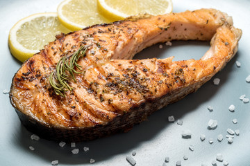 Salmon fillet. Grilled salmon with herb and lemon on plate. Fish roasted on a wooden background.