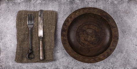 cutlery and wooden plate on a gray table